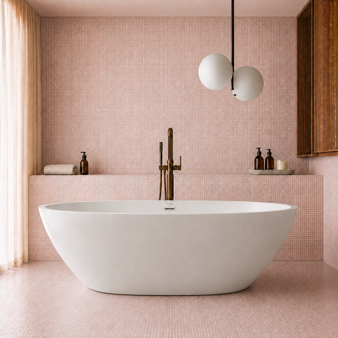 Bloemendaal 69 inch oversized freestanding oval bathtub in a pink tiled bathroom with brass floor-mount faucet, Gramans Bathware
